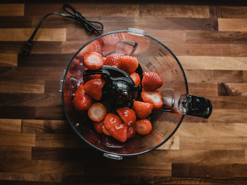 Blend the ingredients Top down view of strawberries in a blender ready to be processed