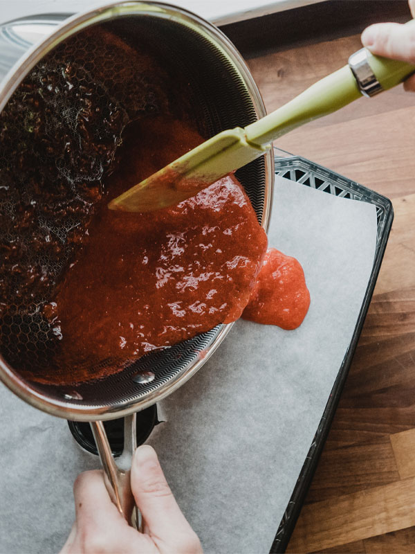 Pour it out Pouring the strawberry fruit leather mixture onto parchment paper