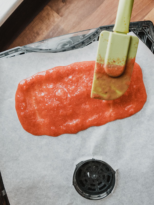 Spread it even Spreading the fruit leather mixture on parchment paper using a rubber spatula